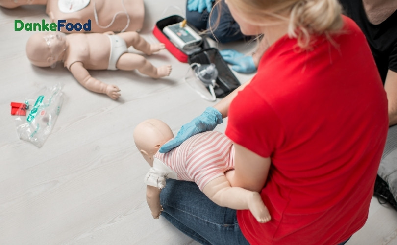 Đặt trẻ nằm sấp, đầu hơi thấp hơn thân thể là một trong các bước sơ cứu trẻ bị sặc sữa  